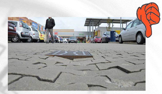 Das Bild zeigt einen öffentlichen Parkplatz mit losen Gehwegplatten.
